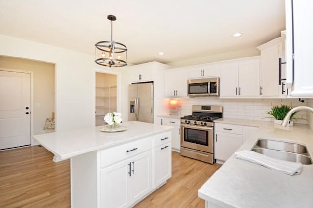 kitchen featuring stainless steel appliances, a sink, a chandelier, decorative backsplash, and light countertops