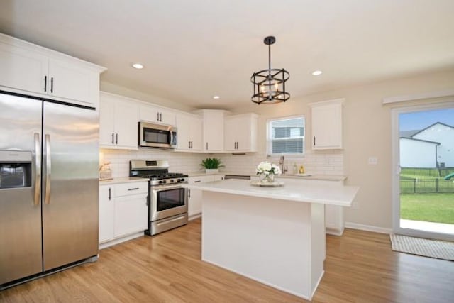 kitchen with tasteful backsplash, light wood-type flooring, light countertops, white cabinets, and appliances with stainless steel finishes