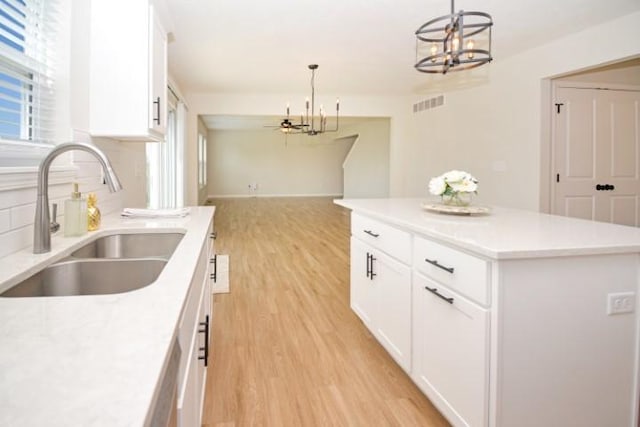 kitchen with light wood-style flooring, a sink, visible vents, a notable chandelier, and light countertops