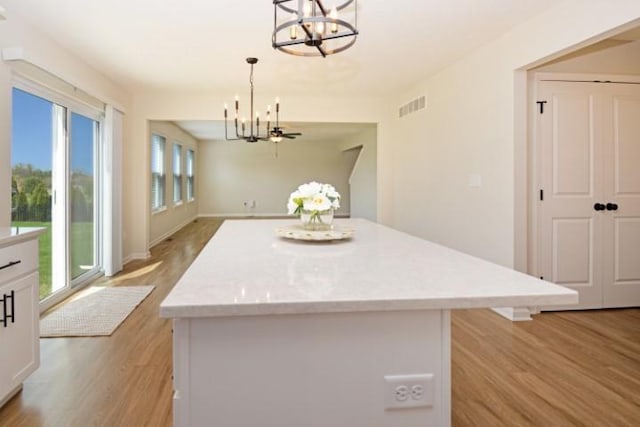 kitchen with white cabinetry, light wood finished floors, a chandelier, and visible vents