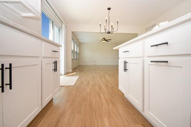 corridor with light wood-type flooring, baseboards, and an inviting chandelier