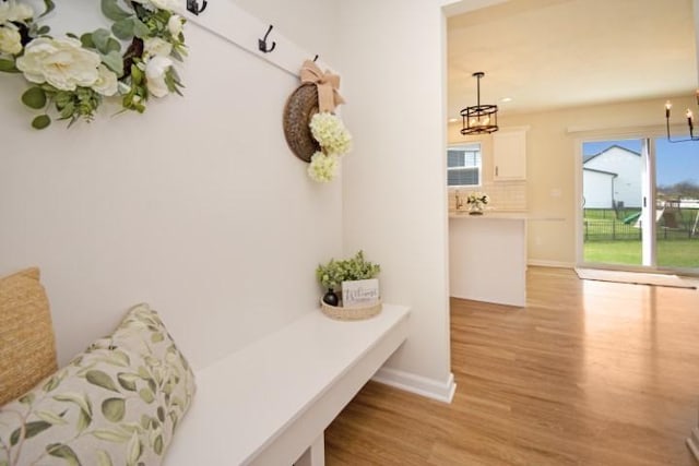 mudroom with baseboards, an inviting chandelier, and light wood-style flooring