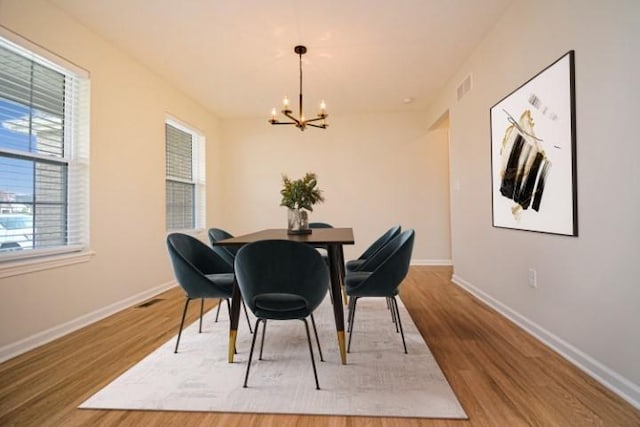 dining room with an inviting chandelier, wood finished floors, visible vents, and baseboards