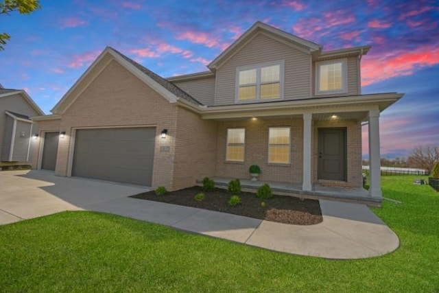 traditional home with a porch, concrete driveway, a garage, brick siding, and a front yard