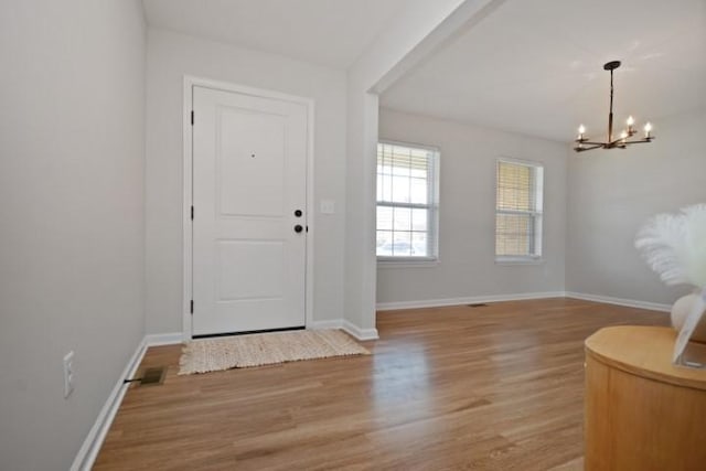 entrance foyer featuring baseboards, wood finished floors, and a chandelier