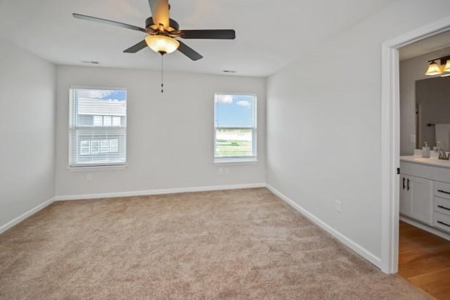 unfurnished bedroom with baseboards, light colored carpet, and a sink