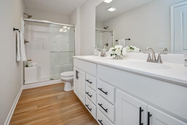 full bath featuring toilet, a sink, double vanity, and a stall shower