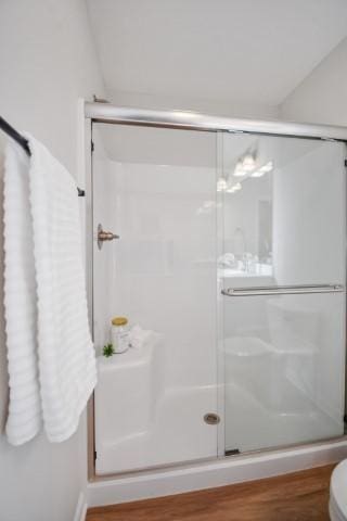 bathroom with wood finished floors and a stall shower