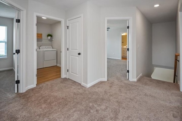 corridor with baseboards, washing machine and clothes dryer, an upstairs landing, and carpet