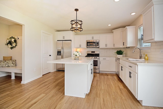 kitchen with appliances with stainless steel finishes, tasteful backsplash, a sink, and a kitchen island
