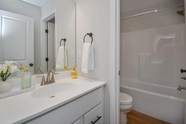 bathroom featuring toilet, washtub / shower combination, vanity, and wood finished floors