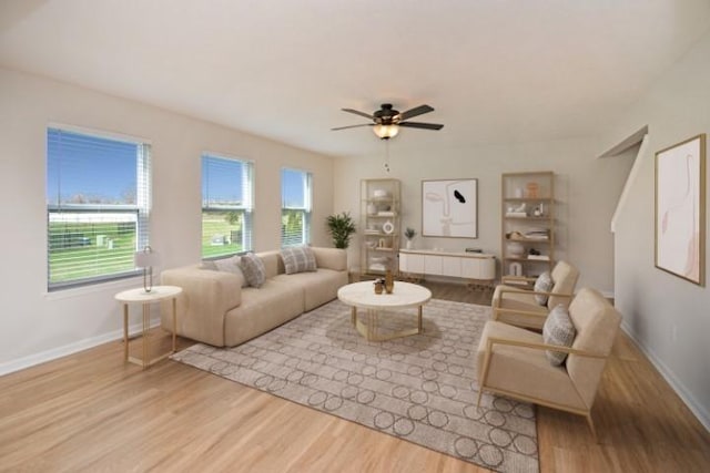 living area with baseboards, a ceiling fan, and wood finished floors