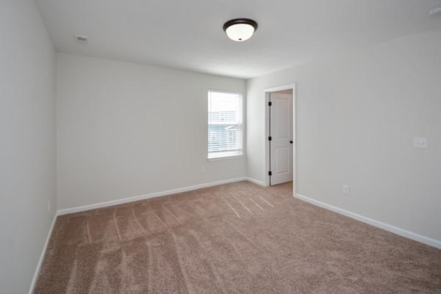 spare room featuring carpet floors and baseboards