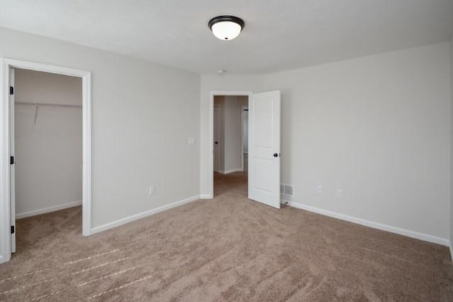 unfurnished bedroom with carpet flooring, a spacious closet, and a closet