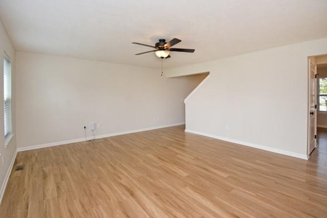 spare room featuring ceiling fan, baseboards, and light wood-style flooring