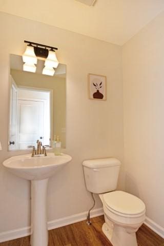 bathroom featuring wood finished floors, baseboards, and toilet
