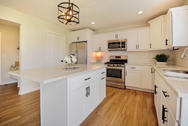 kitchen with decorative backsplash, appliances with stainless steel finishes, a sink, and light wood finished floors