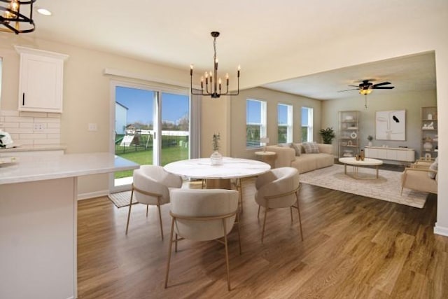 dining area with baseboards, a healthy amount of sunlight, dark wood-style floors, and an inviting chandelier