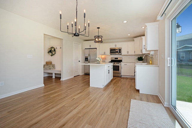 kitchen with stainless steel appliances, a center island, an inviting chandelier, backsplash, and light countertops