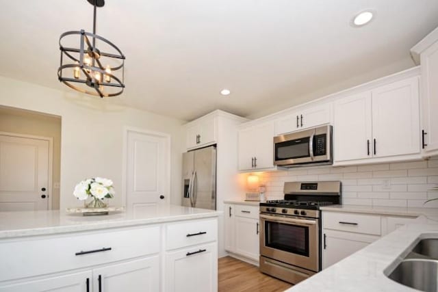 kitchen with light countertops, white cabinetry, stainless steel appliances, and an inviting chandelier