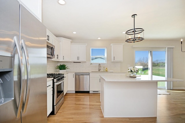 kitchen with a sink, a chandelier, light countertops, backsplash, and appliances with stainless steel finishes