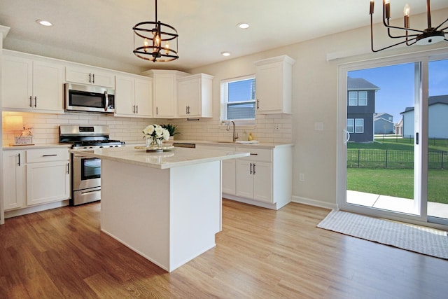 kitchen featuring a notable chandelier, appliances with stainless steel finishes, a sink, and light wood-style floors