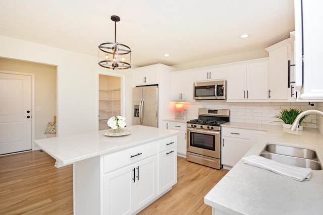 kitchen with tasteful backsplash, a sink, light wood-style floors, an inviting chandelier, and stainless steel appliances
