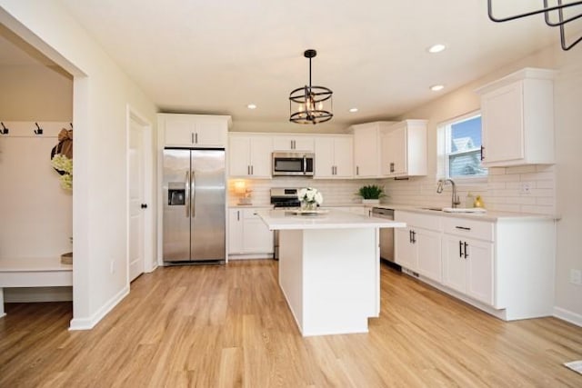 kitchen featuring stainless steel appliances, a center island, a sink, light wood-style floors, and light countertops