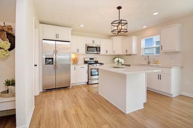 kitchen featuring white cabinets, light countertops, light wood-style flooring, tasteful backsplash, and appliances with stainless steel finishes