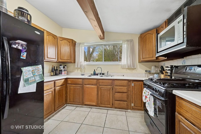 kitchen with a sink, light countertops, brown cabinetry, and black appliances