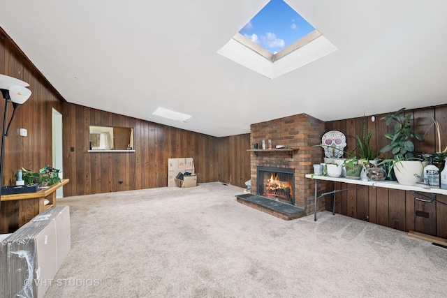 living room with carpet flooring, wood walls, vaulted ceiling with skylight, and a fireplace