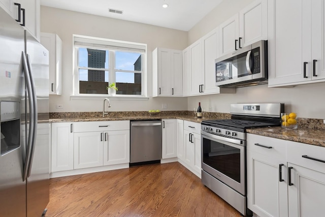 625 W Patterson Ave Unit 3E, Chicago, IL 60613 - kitchen featuring stainless steel appliances, light wood-style flooring, white cabinets, dark stone counters, and a sink