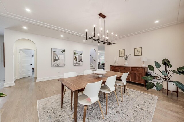 dining room featuring recessed lighting, a notable chandelier, arched walkways, and light wood-style floors
