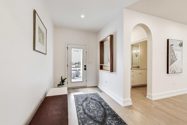 doorway to outside featuring baseboards, light wood-style floors, and recessed lighting