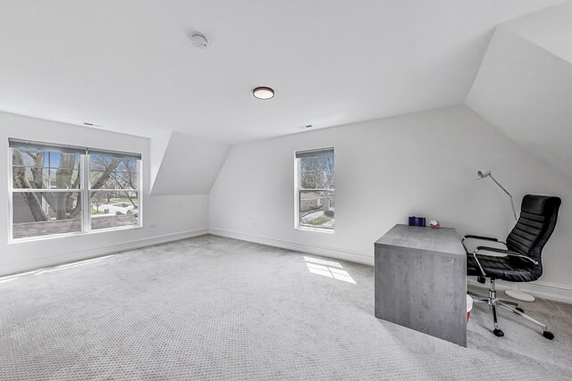 unfurnished office with lofted ceiling, plenty of natural light, and carpet flooring