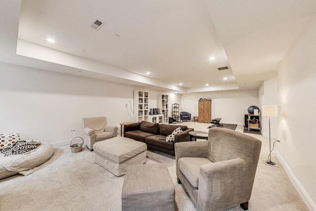 living area with light carpet, baseboards, visible vents, and a tray ceiling