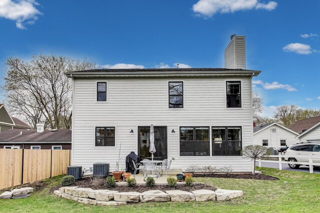 back of property with a chimney, fence, central air condition unit, a patio, and a lawn