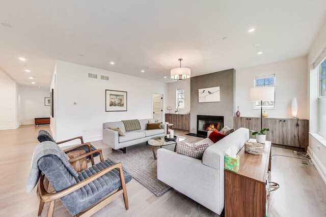 living area with visible vents, light wood-style floors, and a healthy amount of sunlight