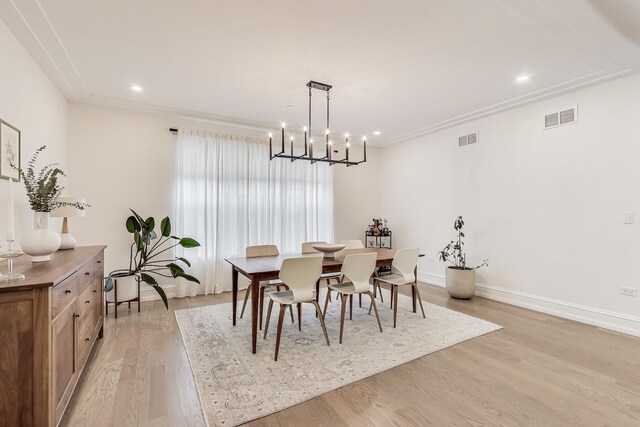dining room with light wood-style flooring, visible vents, baseboards, and an inviting chandelier