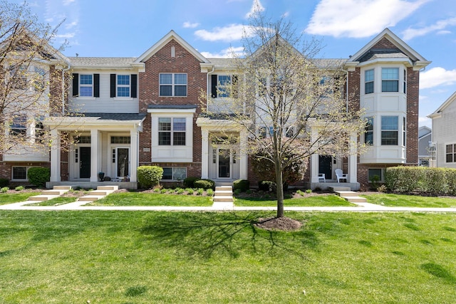 townhome / multi-family property featuring a front yard and brick siding