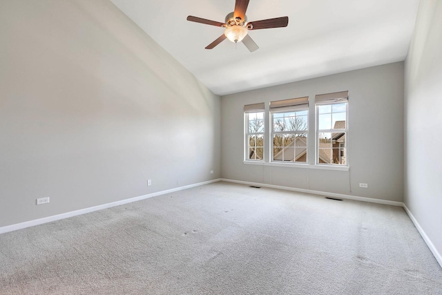 carpeted empty room with a ceiling fan, baseboards, lofted ceiling, and visible vents