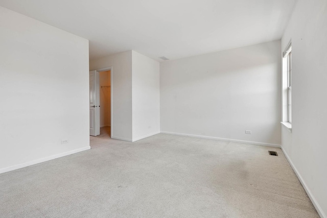 empty room featuring light carpet, visible vents, and baseboards