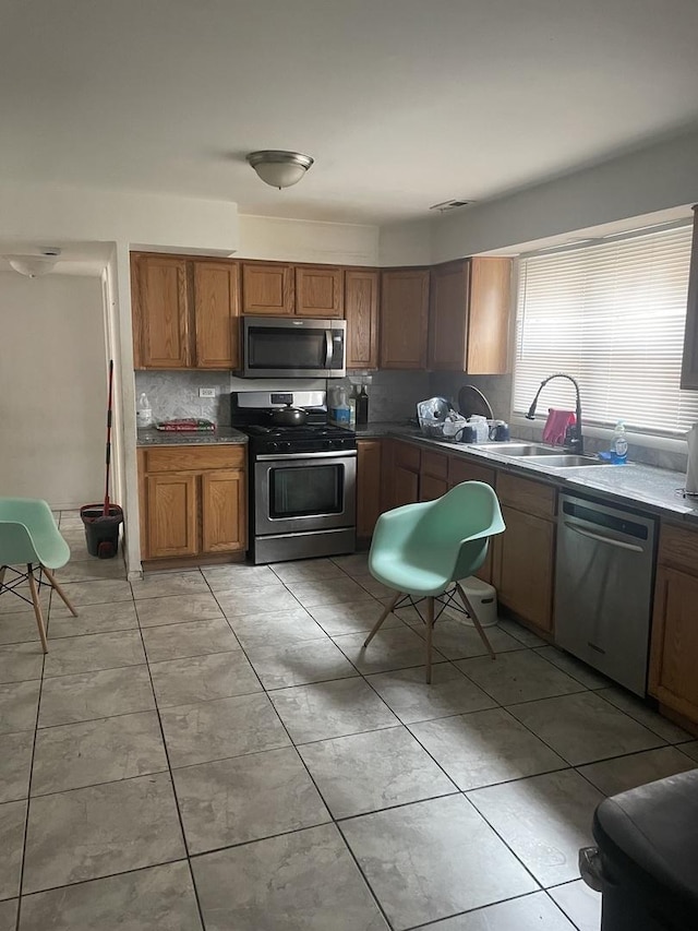 1641 Patricia Pl, Calumet City, IL 60409 - kitchen with tasteful backsplash, light tile patterned floors, a sink, brown cabinets, and stainless steel appliances