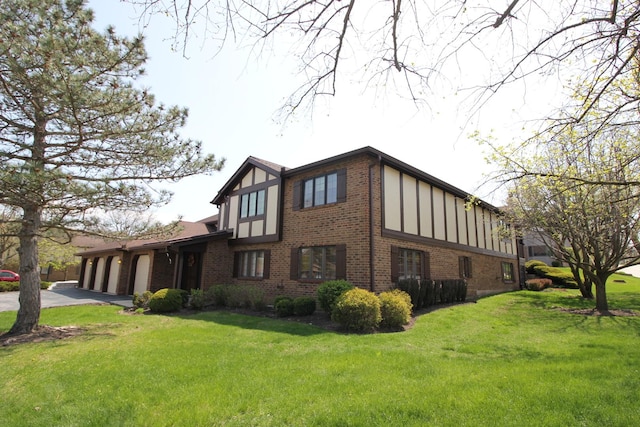 view of side of property featuring a yard, an attached garage, brick siding, and driveway