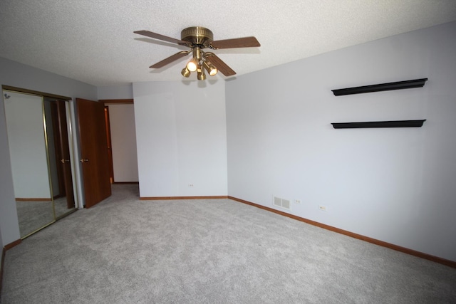 carpeted empty room featuring a ceiling fan, baseboards, visible vents, and a textured ceiling