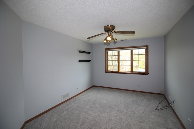 empty room featuring light carpet, a textured ceiling, a ceiling fan, and visible vents