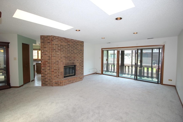 unfurnished living room with recessed lighting, baseboards, a skylight, a fireplace, and light colored carpet