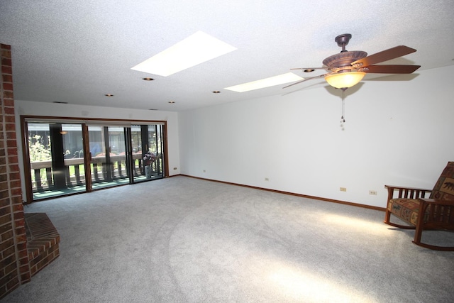 interior space featuring a ceiling fan, baseboards, a skylight, and a textured ceiling