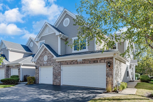 view of front facade with a garage, brick siding, and aphalt driveway