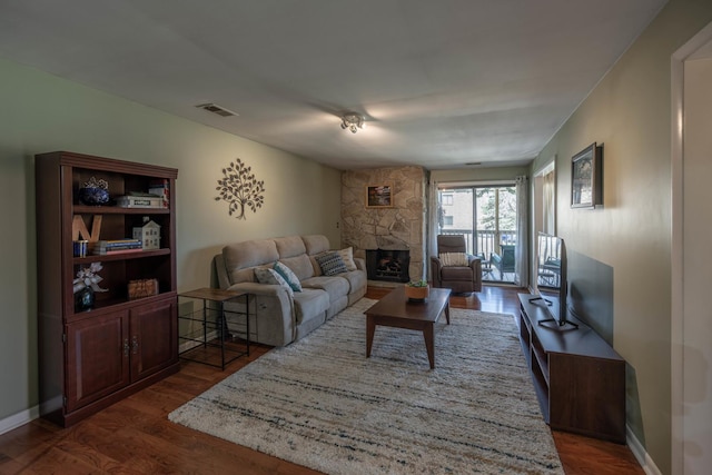 living area with dark wood-style floors, baseboards, visible vents, and a fireplace